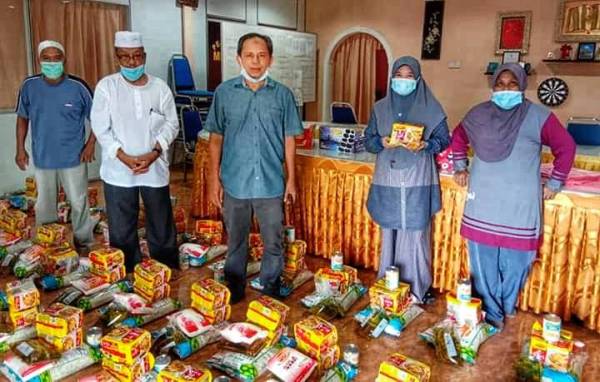 Razak (tengah) bersama barangan asas Felda yang diagihkan buat peneroka 