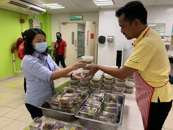 Kamarul (kanan) dan Siuew Luan menyiapkan juadah yang diagihkan di Tesco Kota Bharu kelmarin.