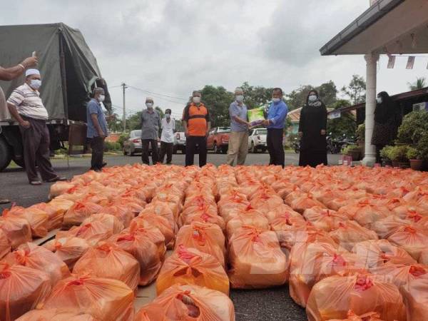 Penyelaras DUN Senaling, Md Rais Basiron (dua dari kanan) menyerahkan sekampit beras kepada salah seorang ketua blok sebagai gimik penyerahan bantuan.