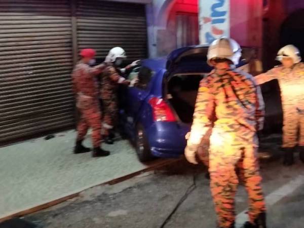 Anggota bomba membantu mengeluarkan mangsa yang tersepit selepas kereta dinaiki terbabas melanggar bangunan kedai di Jalan Besar di sini lewat petang tadi. - Foto JBPM