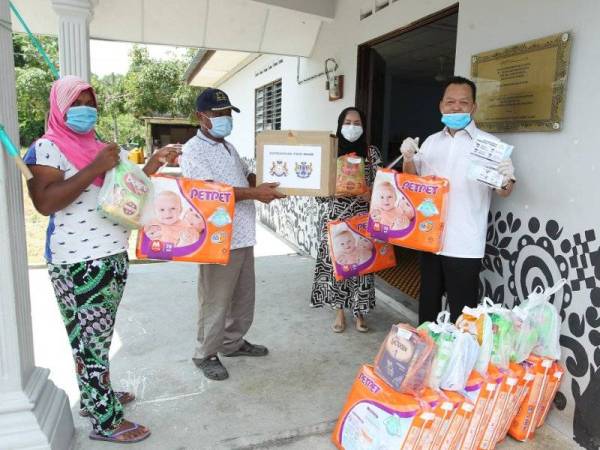 Abdul Rashid (kanan) menyerahkan sumbangan barangan asas bayi kepada salah seorang ibu muda orang asli.