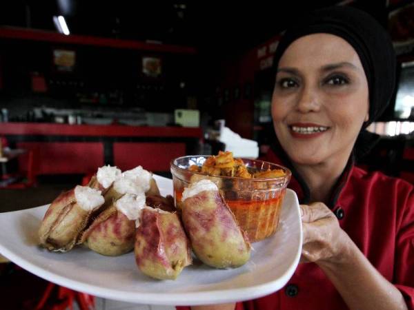 Peniaga restoran, Norhasmah Mohamed Tajuddin menunjukkan lemang periuk kera dan rendang ayam Perak yang siap dimasak di Bukit Chandan hari ini.- Foto Bernama