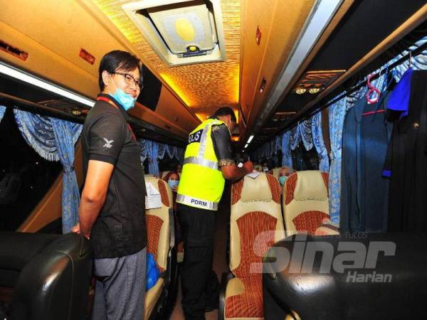 Dr Hendrik (kiri) meninjau keadaan bas yang akan menghantar pulang pelajar ke zon tengah malam tadi.