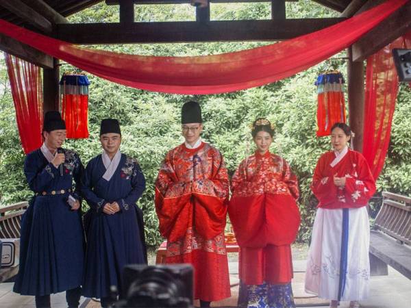 Jialun (tengah) dan Yitong ketika majlis perkahwinan mereka yang diadakan secara live streaming di Hangzhou, wilayah Zheijiang pada 1 Mei lalu. - FOTO: AFP