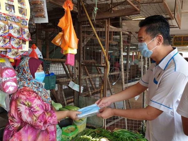 Kok Seong mengedarkan topeng muka kepada peniaga Pasar Besar Bahau.