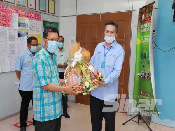 Che Abdullah (kiri) menerima cenderamata daripada Nik Roslan ketika sesi lawatan beliau hari ini.