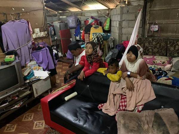 Fauzi (kiri) bersama tiga anaknya di rumah mereka di Lundang, disini.