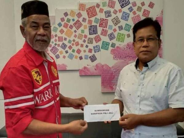 Kamarudin (kiri) menerima sumbangan daripada Zahari. - Foto TRW