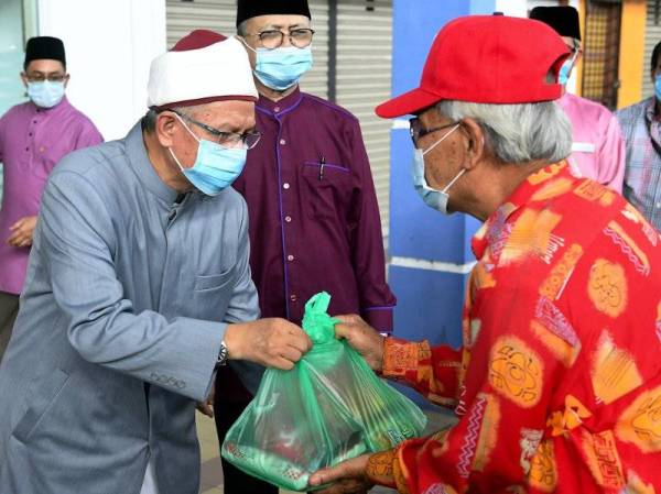 Dr Zulkifli (kiri) menyampaikan sumbangan barangan keperluan harian kepada seorang warga emas pada program Bantuan Hari Raya Kepada Golongan Asnaf hari ini. - Foto Bernama