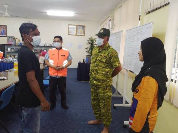 Syazwan ( kiri) berbual dengan Tukimin (dua dari kiri) bersama anggota sukarelawan di Kem Wawasan Negara Gunung Pulai.