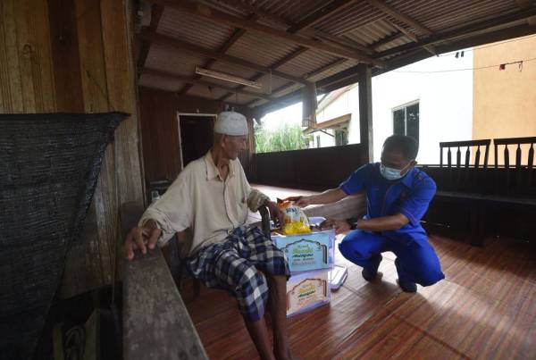 Sudin (kiri) menerima sumbangan Kotak Rezeki Aidilfitri yang disampaikan oleh Che Adam di kediaman di Kampung Bukit Berangan, Tepuh di sini hari ini.