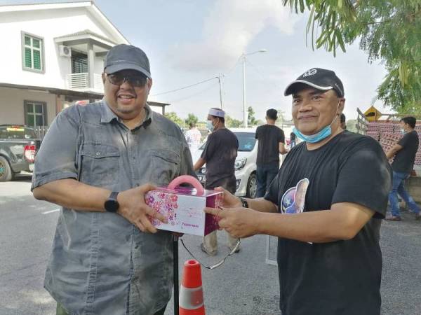 Nor Azman (kanan) menyampaikan cenderahati kepada Ab Rauf selepas program Sumbangan Telur Secara Pandu Lalu di Taman Tangga Batu Permai, di sini hari ini.