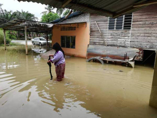 Mariani terpaksa mengharungi banjir setinggi 0.3 meter untuk keluar dari rumahnya di Kampung Padang Serai. Foto: Ihsan pembaca