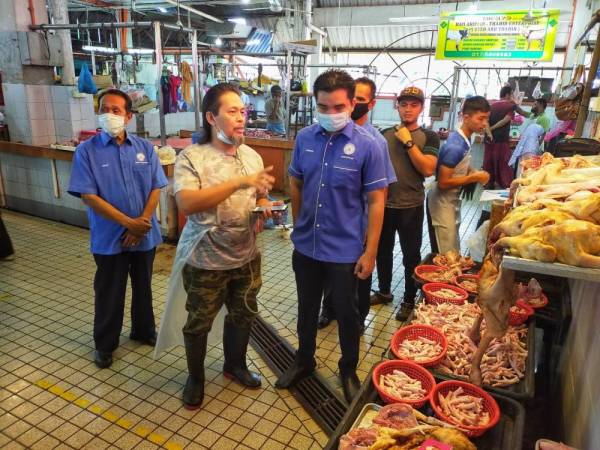 Yusrizal (kanan) mendengar penerangan yang disampaikan oleh Wan Ahmad Fauzi berkenaan harga ayam ketika melakukan pemantuan di Pasar Besar di sini hari ini.