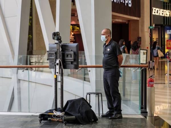 Pengawal keselamatan yang memakai topeng ketika mengoperasikan pengimbas suhu pengimejan termal FLIR di Jewel Mall, Lapangan Terbang Changi, Singapura baru-baru ini. - Foto 123RF