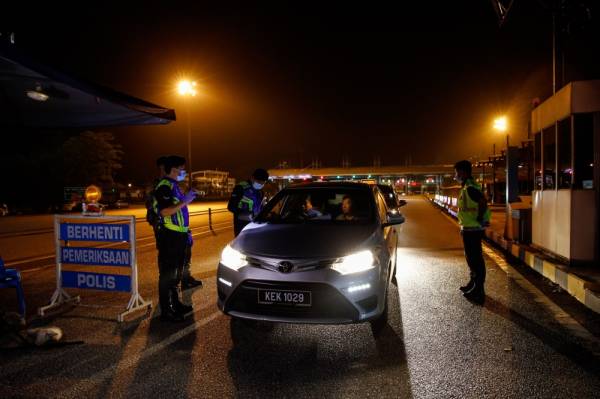 Anggota Polis membuat pemeriksaan ke atas pemandu kenderaan di Plaza Tol Gombak ekoran sekatan jalan raya bagi menyaring pemandu yang masih mahu pulang menyambut Aidilfitri di kampung ketika tinjauan malam tadi. -Foto Bernama