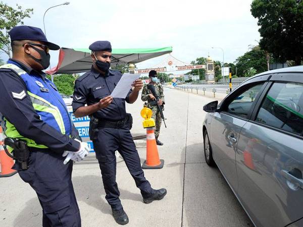 Anggota polis memeriksa surat kebenaran rentas negeri ketika mengadakan sekatan jalan raya bagi memantau kenderaan yang melakukan pergerakan rentas negeri tanpa kebenaran untuk menyambut perayaan Aidilfitri ketika tinjauan Bernama di Plaza Tol Alor Setar (arah utara). - Foto Bernama