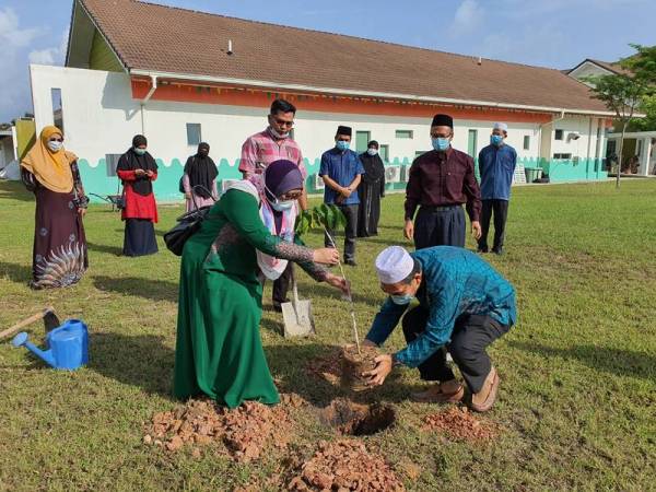 Dr Azura (kiri) dan Mohd Taufek (kanan) menanam pokok merbau di pekarangan Pejabat LPPKN Kepala Batas.