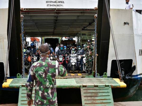 Tentera Indonesia mengawasi para penumpang yang bersedia menaiki feri di pelabuhan Ulee Lheu di Banda Aceh untuk memastikan mereka memakai topeng muka. - Foto AFP