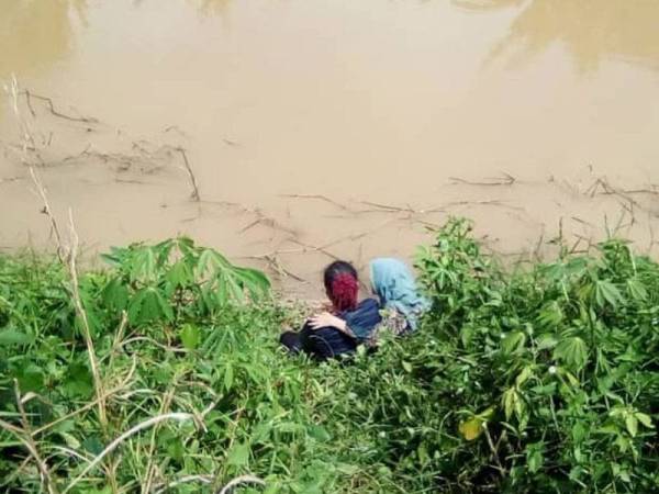 Mangsa berada di tebing tali air dalam keadaan tidak bermaya sementara menunggu bantuan ambulans. - Foto pembaca