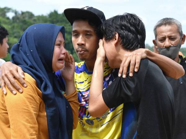 Anggota keluarga mangsa tidak dapat menahan sebak selepas penemuan mayat seorang lagi mangsa lemas iaitu Khairil Firdaus Mohd, 17, yang ditemui di Sungai Terengganu, Kampung Kuala Telemong hari ini. - Foto Bernama