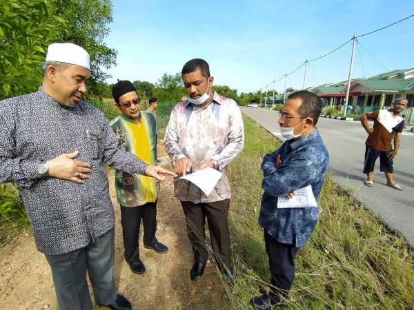 Dr Izani (kiri) meninjau kawasan yang digenangi air akibat banjir kilat di Taman Wadi Imam hari ini.