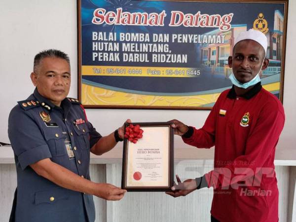 Mohd Zaki menyampaikan surat penghargaan kepada Nor Iman di Balai Bomba dan Penyelamat Hutan Melintang hari ini.