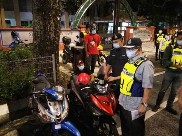 Mazlan (kanan) melihat motosikal yang ditahan dalam Op Bersepadu di Jalan Raja Laut di sini malam tadi.