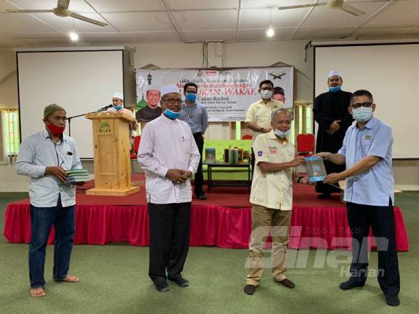 Muhammad Nasir (dua dari kanan) menyerahkan al-Quran wakaf kepada salah satu jabatan dari Bachok hari ini.