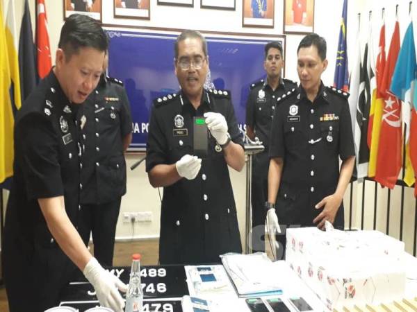 Mohd Padzli (tengah) dan Timbalannya, Superitendan Lim Jit Huey (kiri) menunjukkan telefon bimbit dan cecair peluntur yang digunakan ah long untuk menakut-nakutkan dan mengugut mangsanya, pada sidang akhbar di IPD Johor Bahru Selatan, Larkin, Johor Bahru, hari ini.