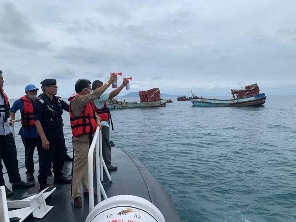 Che Abdullah (tiga dari kiri) membunyikan hon sebagai tanda bermulanya operasi menenggelamkan bot-bot berkenaan.