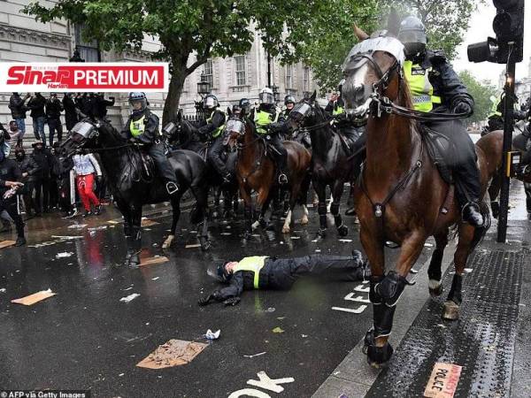 Seorang anggota polis terbaring di jalan raya selepas terjatuh dari seekor kuda di Whitehall, tengah London pada Sabtu lalu. - Gambar AFP