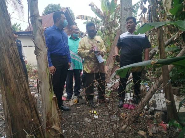 Rahmad (kanan) melihat keadaan belakang di sebuah rumah penduduk di Kampung Bukit Pulau yang tidak mementingkan aspek kebersihan.