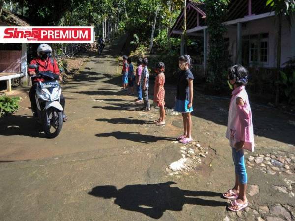 Henrikus Suroto yang menungang motosikal tiba untuk mengajar di rumah muridnya di Magelang, Jawa Tengah baru-baru ini. - Foto AFP