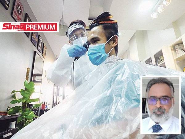 Pekerja kedai gunting rambut, berpakaian lengkap perlindungan diri (PPE) menggunting rambut pelanggan. - Foto Bernama (Gambar kecil: Anandakrishnan)