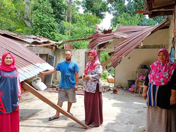 Rumah usang milik Norhasirah (dua dari kanan) dan suaminya ditimpa pokok kekabu dalam kejadian ribut.