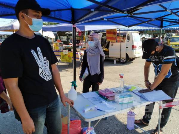 Buku daftar masuk dan pengambilan suhu badan pengunjung dilakukan sebelum dibenarkan masuk ke pasar lambak.
