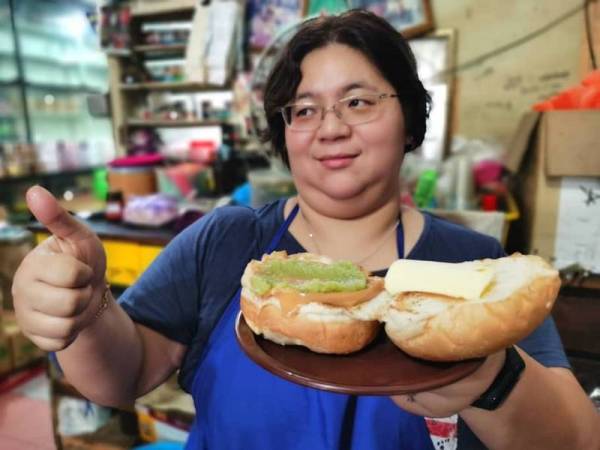 Wong Me Me, 40, menunjukkan 'roti kahwin' yang menjadi pilihan pelanggannya Kedai Kopi Aik Seng, Jalan Wharf di sini. - Foto Bernama