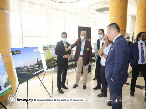 Annuar (dua dari kiri) dan Hamidin (kanan) melawat pameran pada Majlis Pertukaran Dokumen Pembangunan Bandar Bola Sepak Presint 5 di antara Perbadanan Putrajaya, FAM, AFC dan AFF di Putrajaya hari ini. - Foto FAM