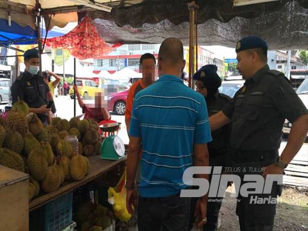 Aminuddin (dua dari kanan) bertanya sesuatu kepada peniaga durian (kiri) yang dikenakan tindakan atas kesalahan menggunakan alat timbang yang tidak sah dan tamat tempoh.