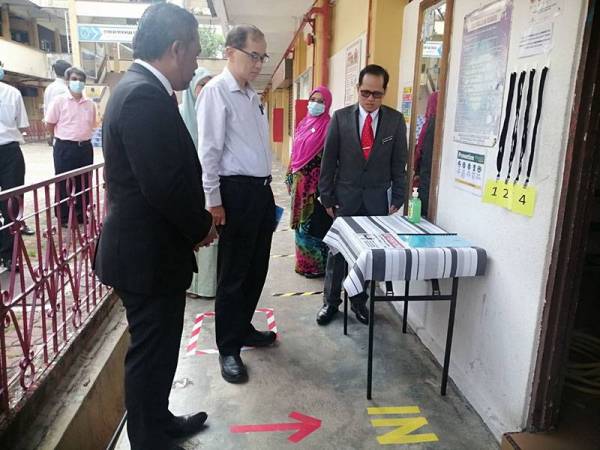 Hang Soon (dua dari kanan) melihat SOP di luar tandas pelajar ketika membuat lawatan kerja SOP buka sekolah normal baharu di Sekolah Menengah Muzaffar Syah (MOZAC), Ayer Keroh di sini hari ini.