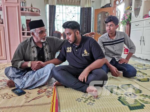 Mohamad Sultan (kiri) menenangkan Mohamed Sadruddin (tengah) yang bersedih setelah menerima berita duka itu di kediaman Allahyarham di Taman Padang Negara di sini.