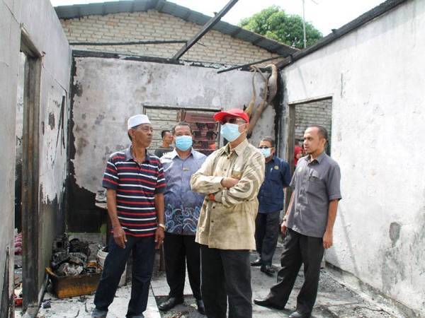 Mohd Asri (tengah) dan Ridzuan (kanan) meninjau rumah mangsa kebakaran di Telok Chengai, Kuala Kedah hari ini.