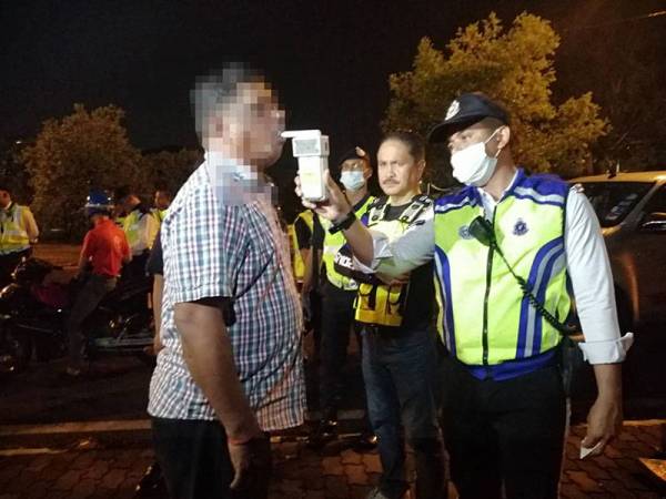 Hasan Basri (dua,kanan) melihat seorang pemandu yang melakukan ujian saringan alkohol ketika Op Mabuk itu.