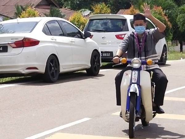 Aksi selamba Mohd Shukri dengan menunggang motosikal Honda Cup ke sidang medianya hari ini.