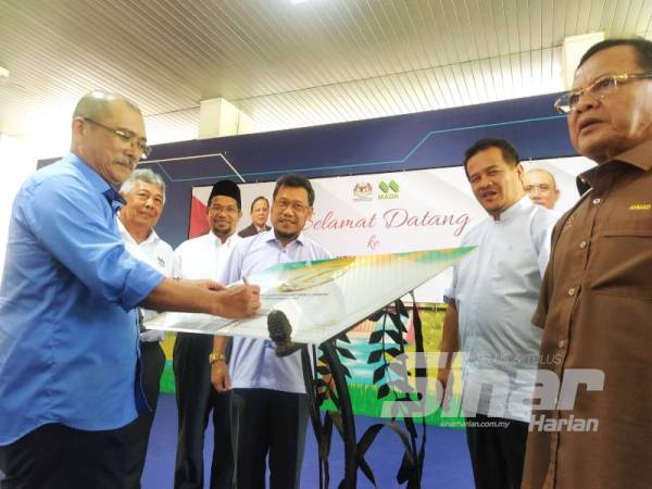 Ronald (tengah) menandatangani plak bersempena 50 tahun penubuhan MADA pada lawatan kerja ke Lembaga Kemajuan Pertanian Muda (MADA), di Ibu Pejabat MADA, Ampang Jajar, di sini, hari ini.