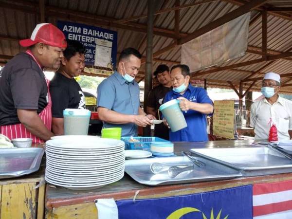 Mohd Sharim bersama Ahmad Maslan menyantuni peniaga warung sekitar Bandar Dara Chini pagi tadi. - Foto Cakna Chini