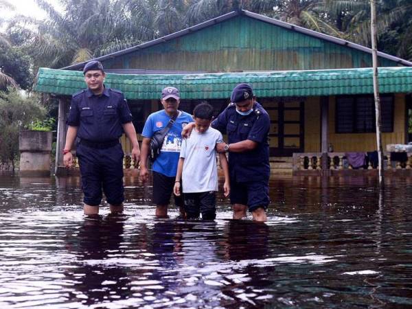 Mansor (belakang) bersama anaknya (depan) ditemani anggota meredah banjir selepas melihat keadaan rumahnya di Kampung Sri Gambut Pekan Nanas hari ini.