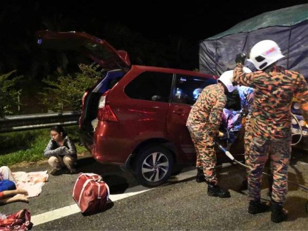 Pasukan bomba membantu mengeluarkan mangsa yang tersepit dalam kenderaan selepas melanggar belakang treler di Tapah hari ini. - Foto JBPM Perak