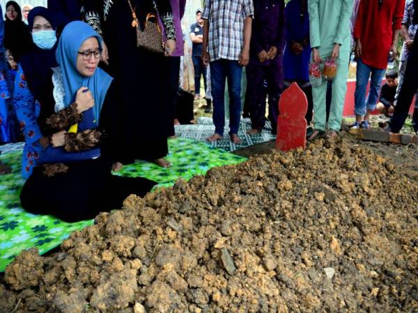 Balu Allahyarham Laskar Kanan PAP Maslim Abd Halim, Nurfaizah Mohd Pagal tidak dapat menahan kesedihan ketika merenung pusara suaminya yang selamat dikebumikan di Kampung Bugaya, Jalan Rancangan hari ini. - Foto Bernama